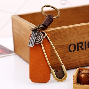 Retro hand-woven brown leather keychain with vintage brass safety pin and metal charm