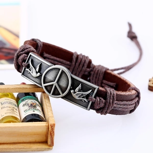 Vintage braided leather bracelet with peace sign and pigeon metal charm on dark brown cord