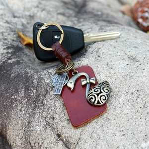 Vintage leather keychain with bronze swan charm and braided strap on a car key