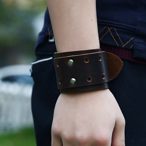 Close-up of brown wide leather punk wristband with silver studs and hole details