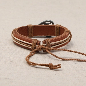 Vintage woven leather bracelet with peace sign charm on a textured linen background