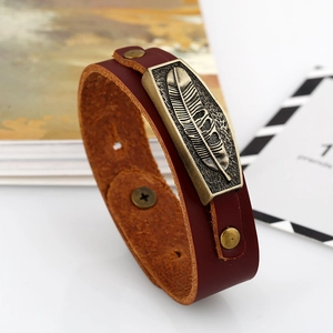 Vintage dark brown leather bracelet featuring a bronze feather charm and snap button clasp