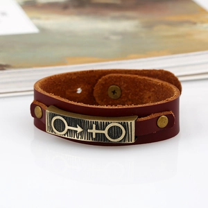 Vintage unisex brown leather bracelet with bronze male and female symbols on white surface