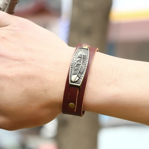 Vintage brown leather wristband with bronze alloy feather charm and rivet details