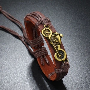 Detailed close-up of brown braided leather bracelet with bronze motorcycle charm