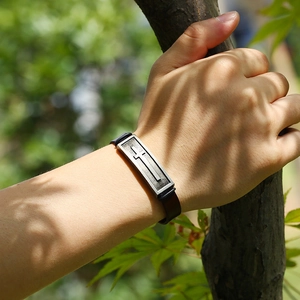 Men's vintage black leather bracelet with a retro silver cross metal charm on wrist