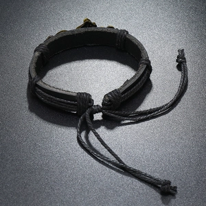 Detailed close-up of retro braided leather bracelet with bronze metal cross accent