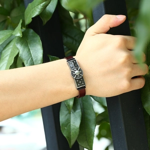Retro brown leather bracelet with engraved silver metal charm on a male wrist