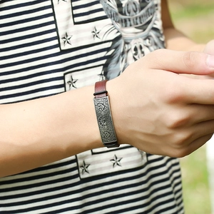 Vintage brown leather bracelet for men with embossed bronze metal plate on a striped wrist