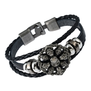 Detail van meerlaagse gevlochten leren armband met vintage metalen schedelbedels