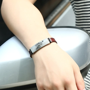 Geflochtenes Lederarmband in Braun mit gravierter Love-Metallplatte am Handgelenk