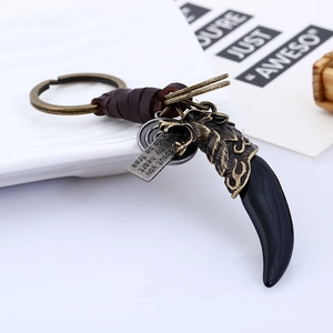 Vintage braided leather keychain with wolf head relief and resin tooth pendant on white plate