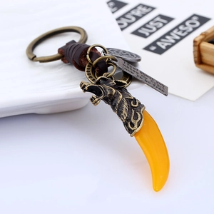 Vintage wolf head keychain with resin tooth pendant and braided leather strap shown at angle