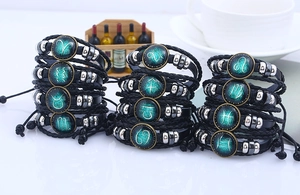 Vista macro di dodici braccialetti zodiacali in pelle intrecciata con cupole in vetro