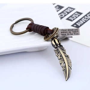Vintage braided leather keychain with bronze feather pendant and engraved metal charm