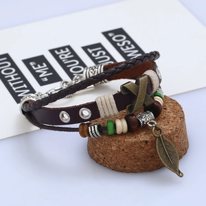 Multilayer leather bracelet with bronze leaf pendant and X metal charm on cork stand