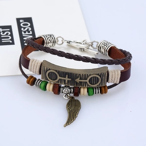 Détail d'un bracelet en cuir multicouche avec breloque aile et plaque en bronze vintage