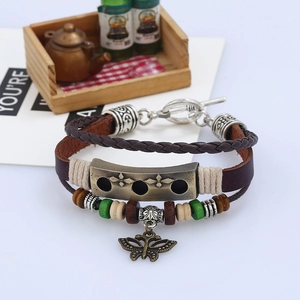 Detail of vintage multilayer leather bracelet with bronze butterfly charm and wooden beads