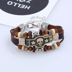 Détail d'un bracelet en cuir multicouche avec plaque tête de mort et perles en bois