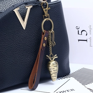 Retro carrot alloy pendant with leather cord on black bag, vintage metal keychain