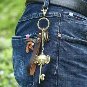 Vintage bronze elephant leather keychain with heart charm hanging on blue denim jeans