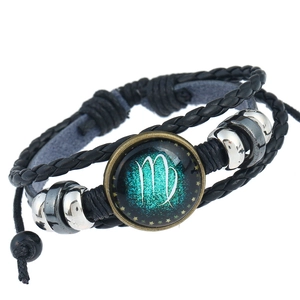 Dettaglio macro del segno zodiacale Vergine su bracciale vintage in pelle intrecciata