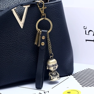 Bronze Buddha statue keychain accessory on black lychee grain leather handbag