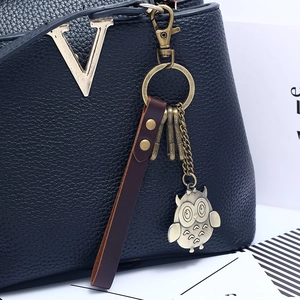 Black pebbled leather keychain bag charm with owl pendant and golden metal V logo detail
