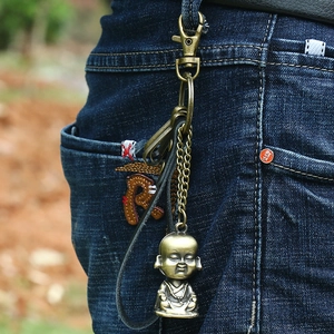 Bronze Buddha monk keychain with leather strap on blue jeans for style showcase