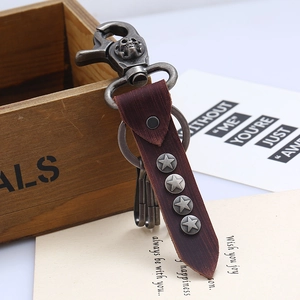 Vintage punk leather keychain with skull buckle and star studs on rustic wood background