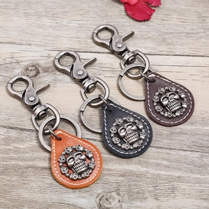 Retro skull leather keychains in brown and teal colors on wooden background