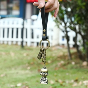 Vintage bronze monk pendant keychain with black leather strap held in hand