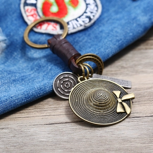 Retro cowboy hat keychain with leather wrap and vintage metal pendants on denim