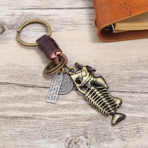 Detail of vintage fishbone keychain with brown leather and bronze engraved charms