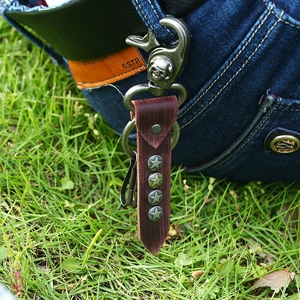 Retro brown leather keychain with metal star rivets and skull clasp on denim background