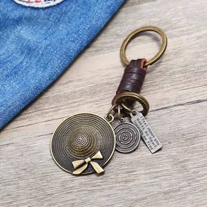 Vintage leather keychain featuring a brass straw hat pendant and circular charms