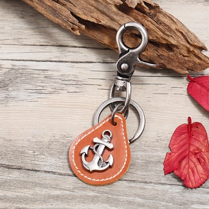 Close-up of vintage bronze anchor pendant on premium leather keychain with autumn leaves