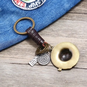Retro leather keychain with bronze hat pendant and engraved tag on wood background