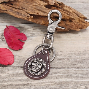 Punk vintage leather skull keychain with metal lobster clasp on a rustic wooden surface