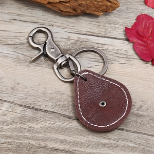Vintage-Schlüsselanhänger aus dunkelbraunem Leder mit silbernem Karabiner auf Holz