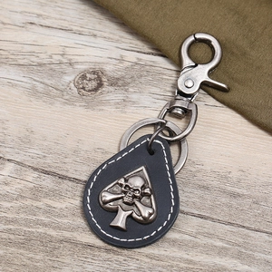 Close-up of black spade leather keychain with silver skull emblem and lobster clasp