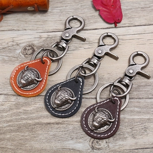 Retro bull head leather keychains in brown and black on a rustic wooden background
