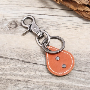 Retro bronze alloy and leather keychain with vintage silver ring on wooden surface