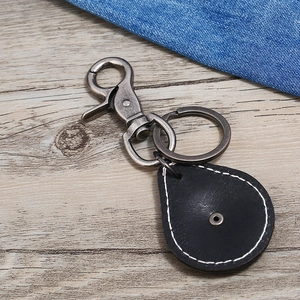 Vintage black leather keychain with silver metal clasp on a light wood background