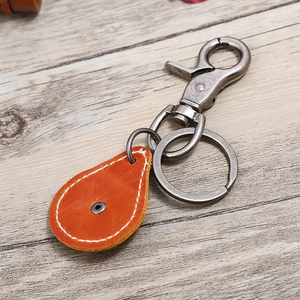 Retro pear-shaped orange leather keychain with vintage silver lobster clasp on wood