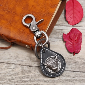 Macro detail of a vintage leather keychain featuring a bull head metal emblem and stitching