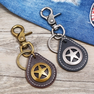 Punk style genuine leather star keychain with vintage metal clasps on a wood background