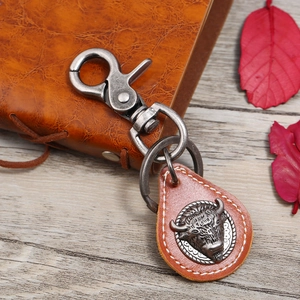 Retro brown leather keychain with bull head metal relief on rustic wood background