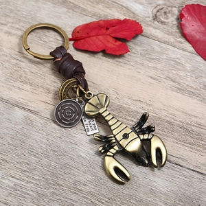 Vintage bronze lobster keychain with hand-woven leather strap and symbolic charms