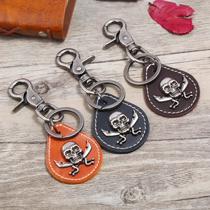 Retro leather skull keychains in three colors on a rustic wooden background